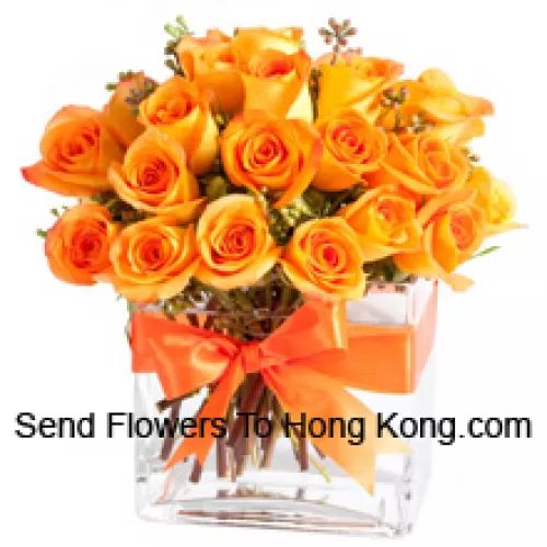 24 roses oranges avec quelques fougères dans un vase en verre